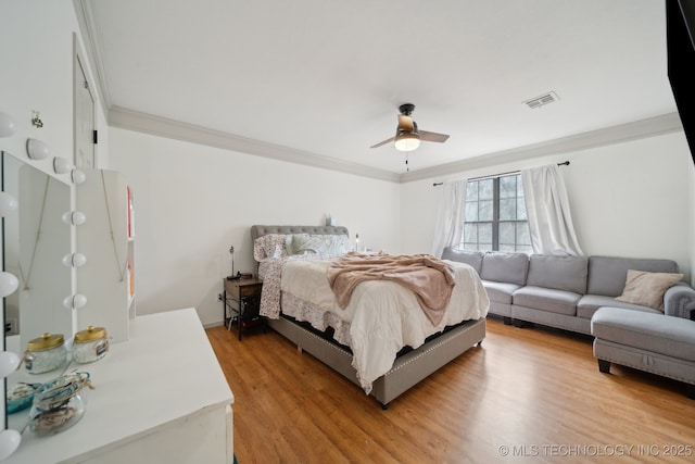 bedroom featuring a ceiling fan, visible vents, ornamental molding, and light wood-style floors