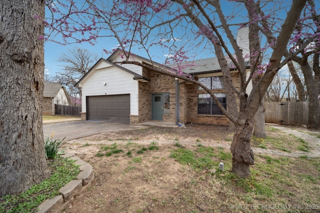 view of front of home with fence, an attached garage, brick siding, a chimney, and driveway