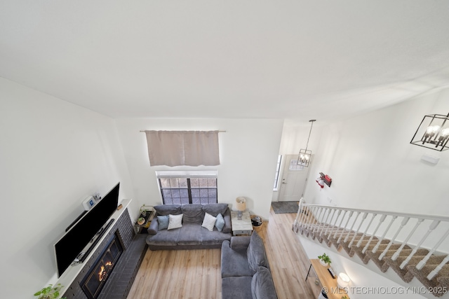 living area featuring a chandelier, wood finished floors, and a fireplace