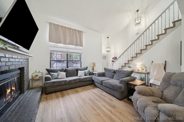 living area with stairway, a fireplace, wood finished floors, and a towering ceiling