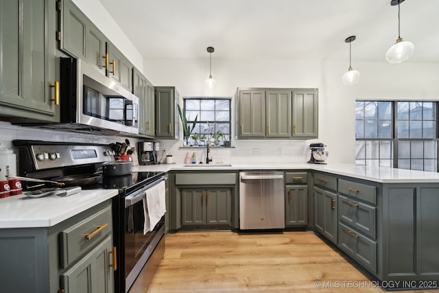 kitchen with backsplash, a peninsula, appliances with stainless steel finishes, and light countertops