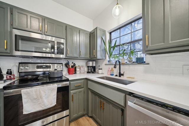 kitchen with a sink, appliances with stainless steel finishes, tasteful backsplash, and light countertops