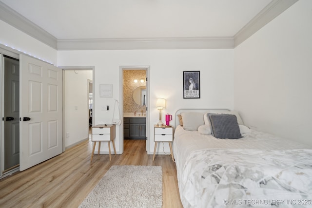bedroom featuring a sink, ornamental molding, wood finished floors, and ensuite bathroom