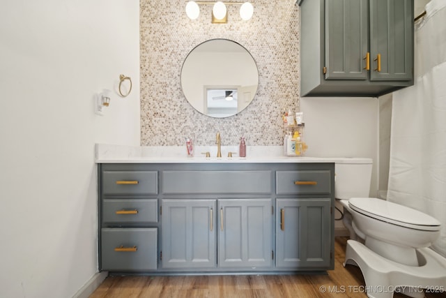 bathroom with toilet, tasteful backsplash, wood finished floors, and vanity