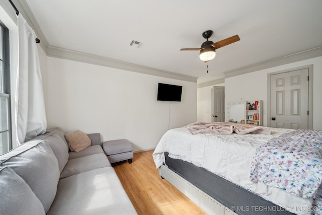 bedroom featuring crown molding, a ceiling fan, wood finished floors, and visible vents