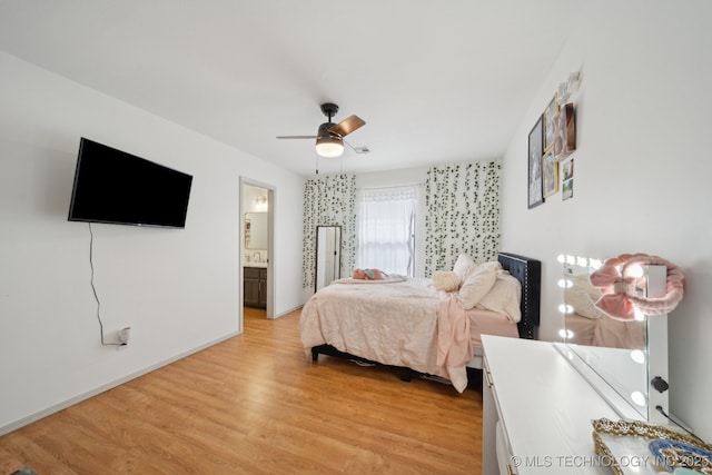 bedroom featuring baseboards, ceiling fan, light wood-type flooring, connected bathroom, and a sink
