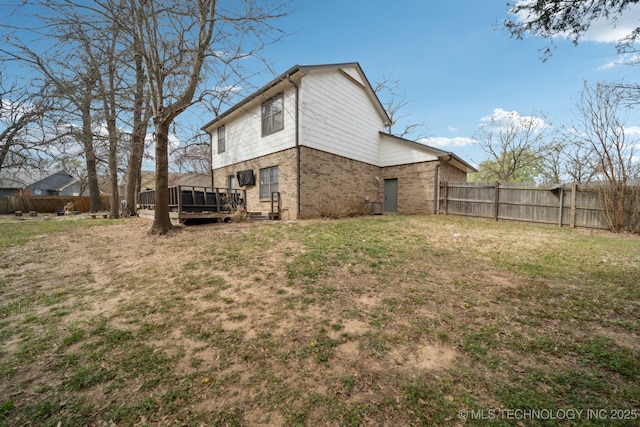rear view of property with a yard, brick siding, a wooden deck, and a fenced backyard