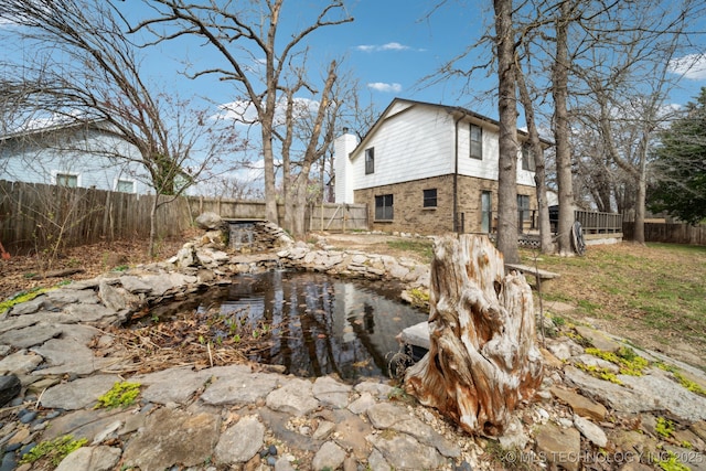 exterior space with a fenced backyard and a garden pond