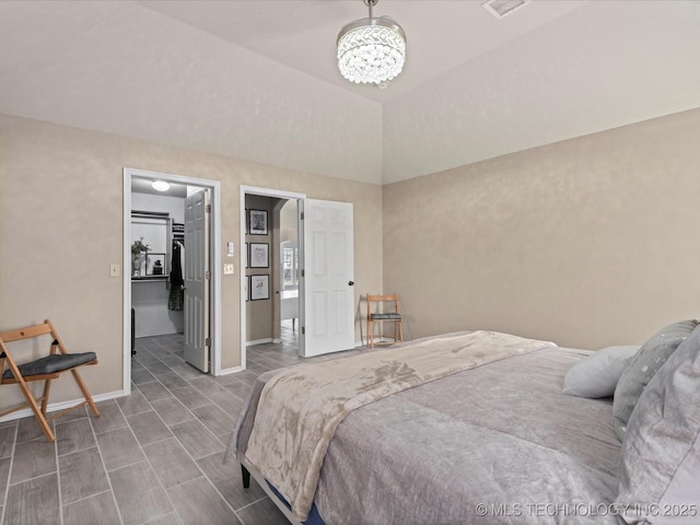 bedroom with a chandelier, a walk in closet, visible vents, and baseboards