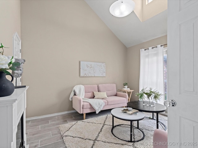 living room featuring a healthy amount of sunlight, high vaulted ceiling, a fireplace with flush hearth, and wood tiled floor