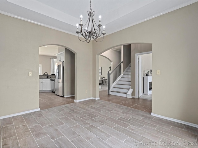 interior space featuring crown molding, arched walkways, a chandelier, and a sink