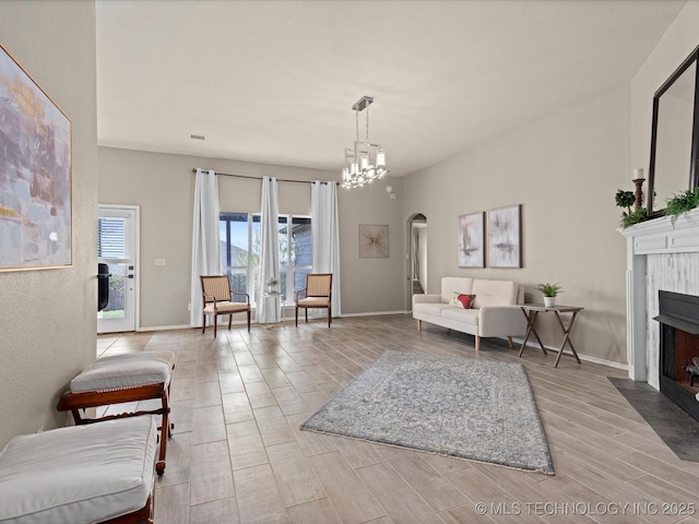 living room with a fireplace with flush hearth, arched walkways, wood finished floors, and baseboards