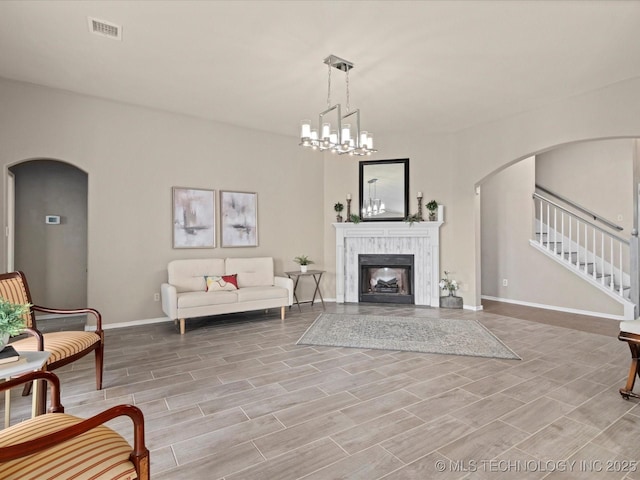 living area featuring light wood-type flooring, baseboards, stairs, visible vents, and arched walkways