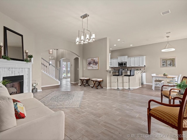 living room featuring arched walkways, a fireplace, baseboards, and visible vents