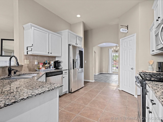 3017 Lincoln Rd, Bartlesville, OK 74006 - kitchen with stainless steel appliances, a sink, arched walkways, white cabinets, and recessed lighting