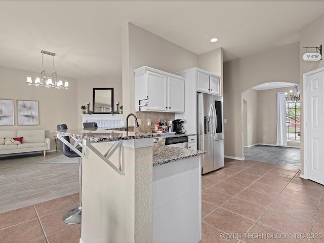 3017 Lincoln Rd, Bartlesville, OK 74006 - kitchen featuring appliances with stainless steel finishes, arched walkways, white cabinets, light stone countertops, and a chandelier