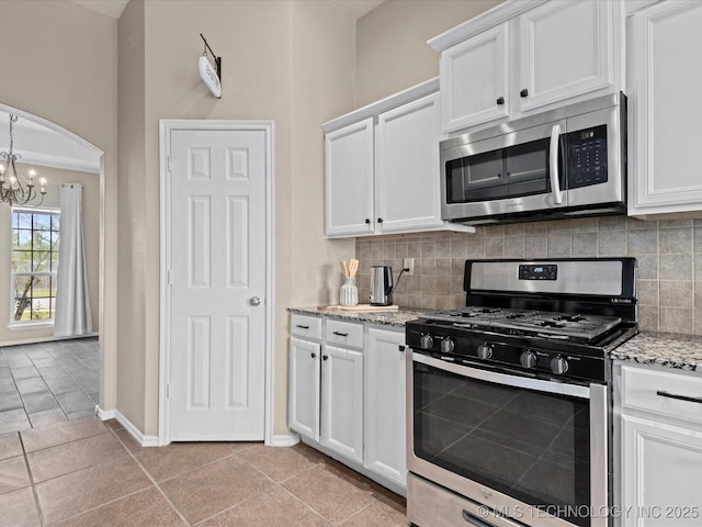 kitchen featuring tasteful backsplash, white cabinetry, a notable chandelier, and stainless steel appliances
