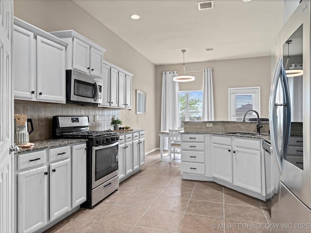 kitchen with dark stone counters, white cabinetry, visible vents, appliances with stainless steel finishes, and decorative backsplash
