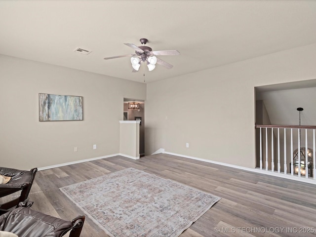 living area featuring visible vents, baseboards, a ceiling fan, and wood finished floors