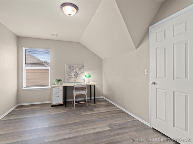 home office featuring visible vents, baseboards, vaulted ceiling, and wood finished floors