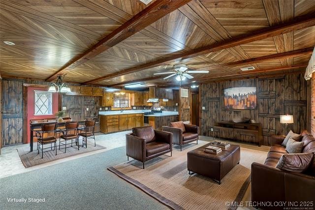 703 N Sioux Ave, Claremore, OK 74017 - living room featuring wood walls, a ceiling fan, and light colored carpet