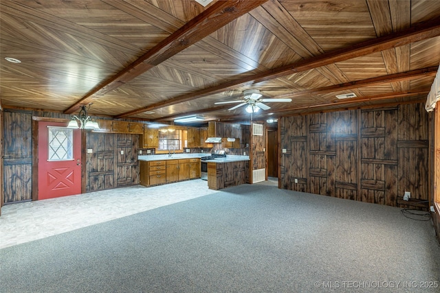 703 N Sioux Ave, Claremore, OK 74017 - kitchen featuring stainless steel range with gas stovetop, brown cabinetry, light countertops, wooden walls, and light carpet