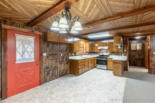 703 N Sioux Ave, Claremore, OK 74017 - kitchen with stainless steel gas stove, wood walls, brown cabinets, under cabinet range hood, and light countertops