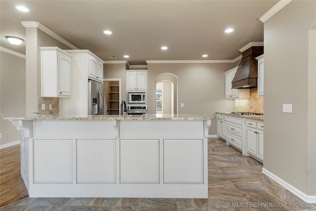 kitchen with stainless steel appliances, custom exhaust hood, crown molding, a peninsula, and baseboards