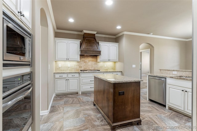 kitchen featuring custom exhaust hood, stainless steel appliances, ornamental molding, and arched walkways