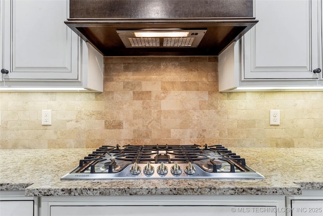 kitchen with tasteful backsplash, ventilation hood, stainless steel gas cooktop, and white cabinets