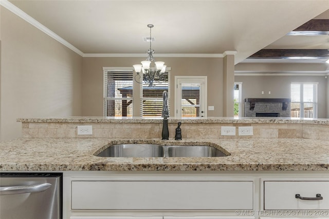 kitchen with stainless steel dishwasher, white cabinets, a sink, a chandelier, and light stone countertops