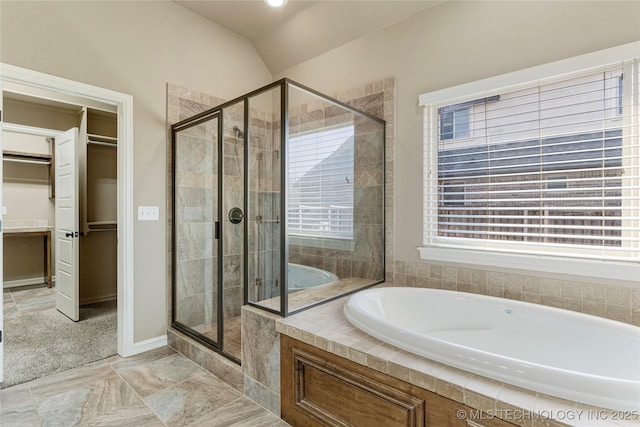 bathroom featuring a bath, a walk in closet, a shower stall, and vaulted ceiling