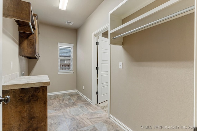 laundry area with baseboards, visible vents, and stone finish floor