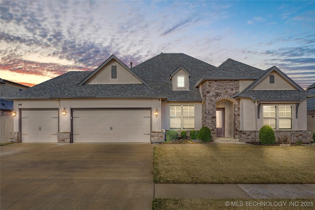 view of front of house featuring stucco siding, a yard, a garage, stone siding, and concrete driveway