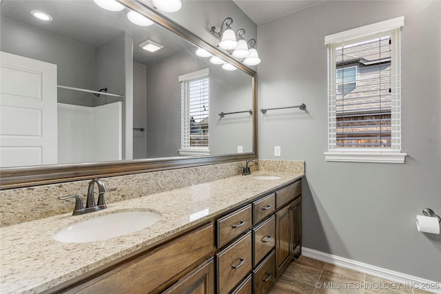 full bath featuring baseboards, tile patterned floors, double vanity, and a sink