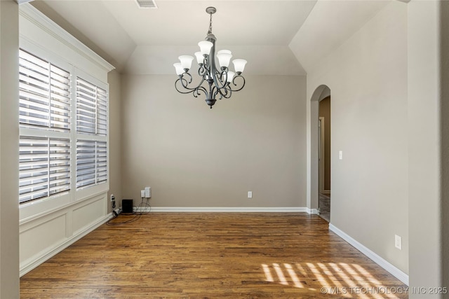 unfurnished dining area featuring a chandelier, visible vents, vaulted ceiling, arched walkways, and wood finished floors