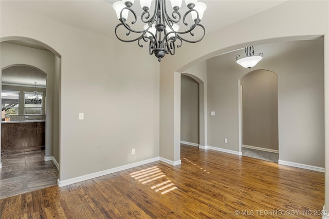 unfurnished dining area featuring a chandelier, baseboards, and wood finished floors