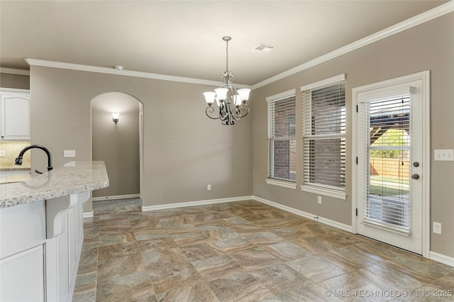 unfurnished dining area featuring crown molding, arched walkways, a sink, and baseboards