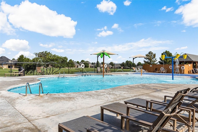 pool featuring fence, a patio area, and a water play area