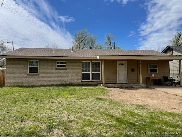 rear view of property with brick siding, a patio, and a lawn