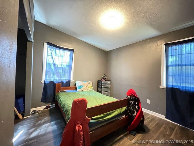 bedroom featuring a textured ceiling, baseboards, and wood finished floors