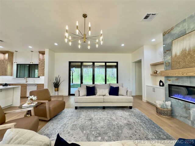 30303 E 59th St S, Broken Arrow, OK 74014 - living room featuring light wood-style floors, recessed lighting, a chandelier, and a fireplace