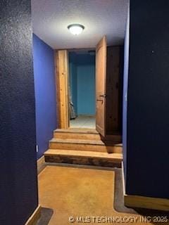 corridor featuring a textured wall and stairs
