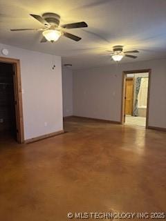 spare room featuring baseboards, ceiling fan, and finished concrete floors