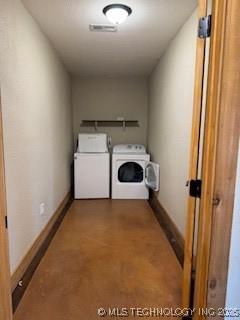 washroom featuring baseboards, separate washer and dryer, and laundry area