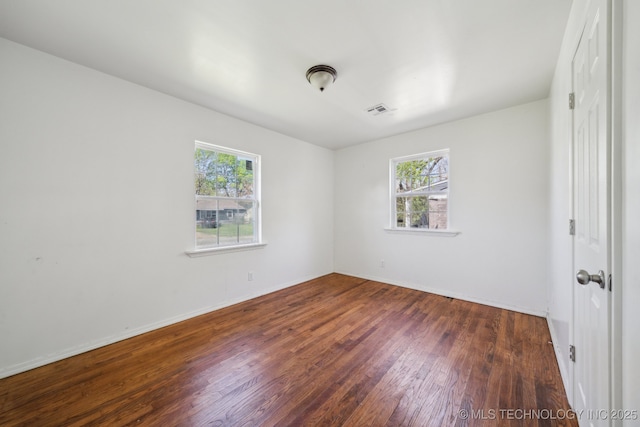 spare room featuring wood finished floors, baseboards, and visible vents