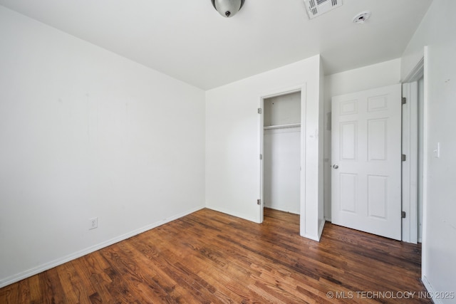 unfurnished bedroom with visible vents, a closet, baseboards, and wood finished floors