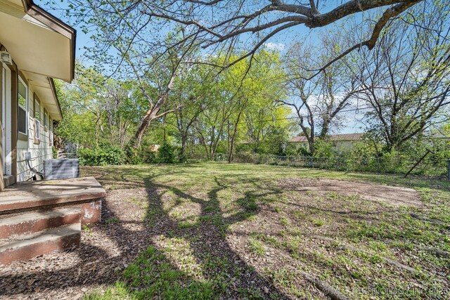 view of yard featuring central AC unit and fence