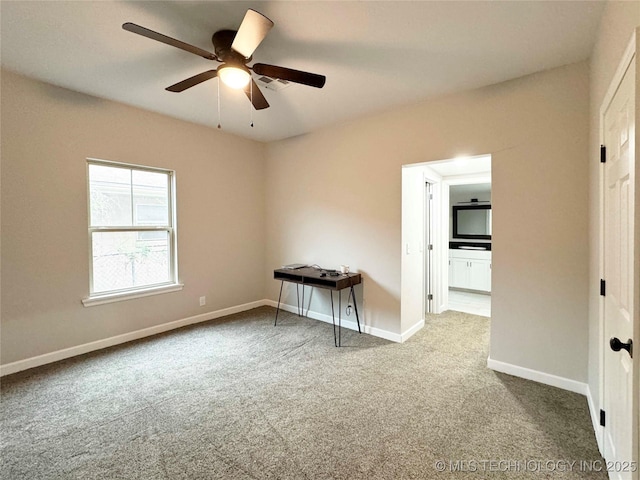 spare room with baseboards, ceiling fan, and carpet