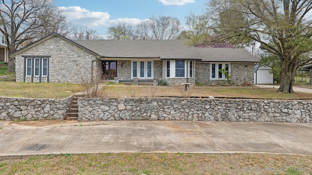 1509 S Mission Ln, Okmulgee, OK 74447 - ranch-style house with stone siding, a front lawn, a shingled roof, an outdoor structure, and a shed